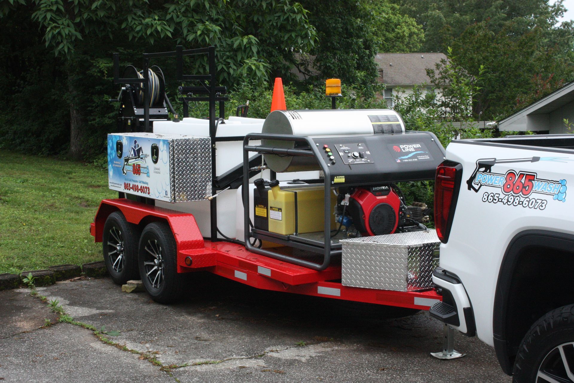 A white truck is parked next to a trailer with a machine on it.