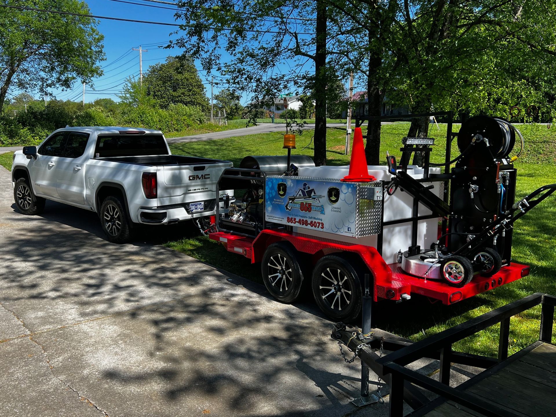 A white truck is towing a trailer with a hose attached to it. 865 Power Wash equipment