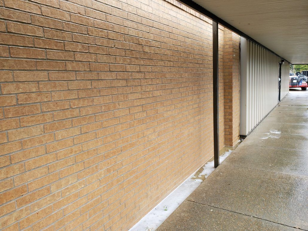 A long hallway with a brick wall and a sidewalk