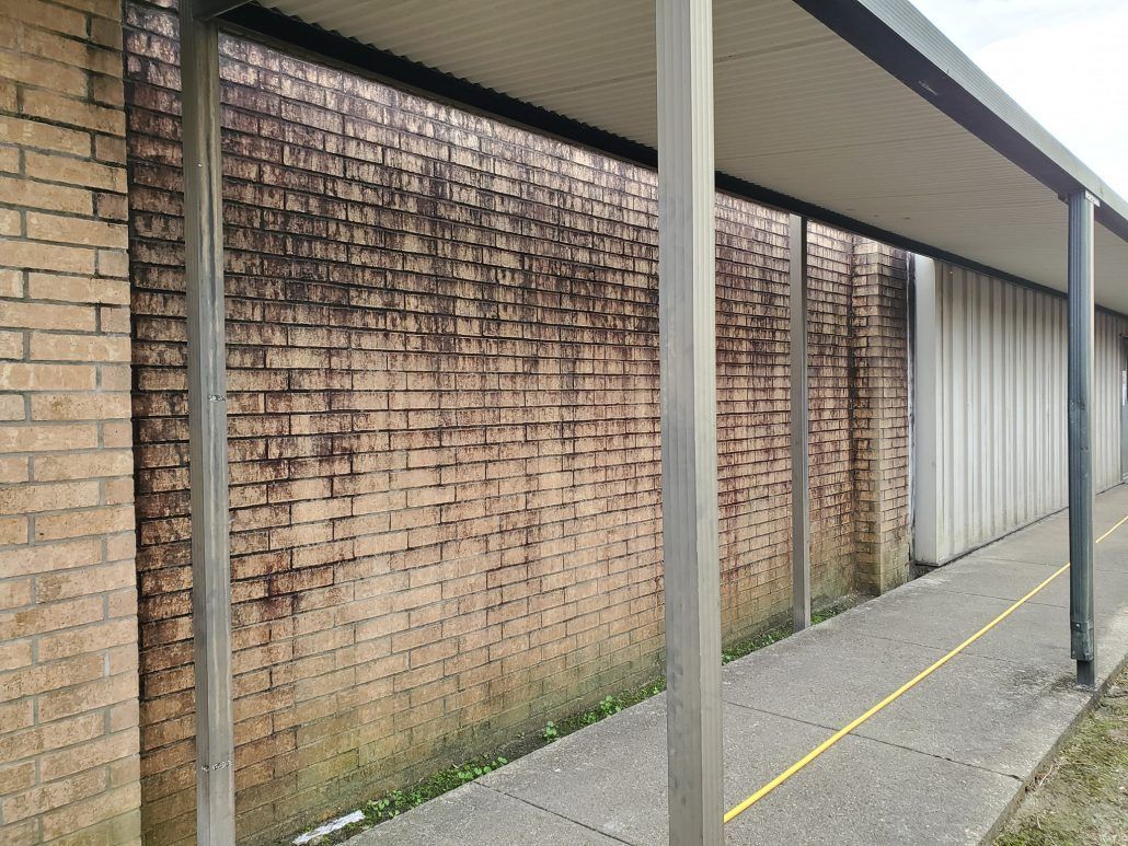 A brick wall with a covered walkway in front of it.