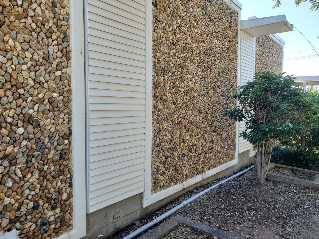 A house with a stone wall and shutters on the side of it.