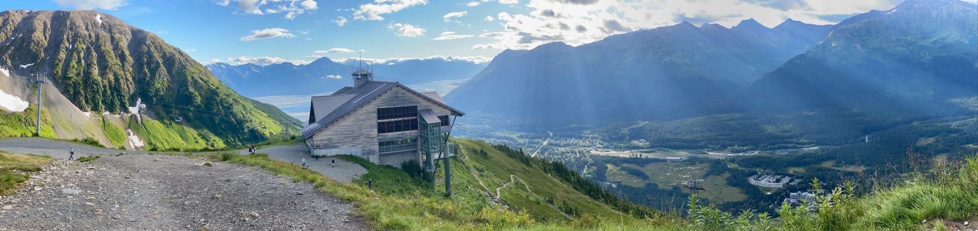 A small house is sitting on top of a hill in the mountains.