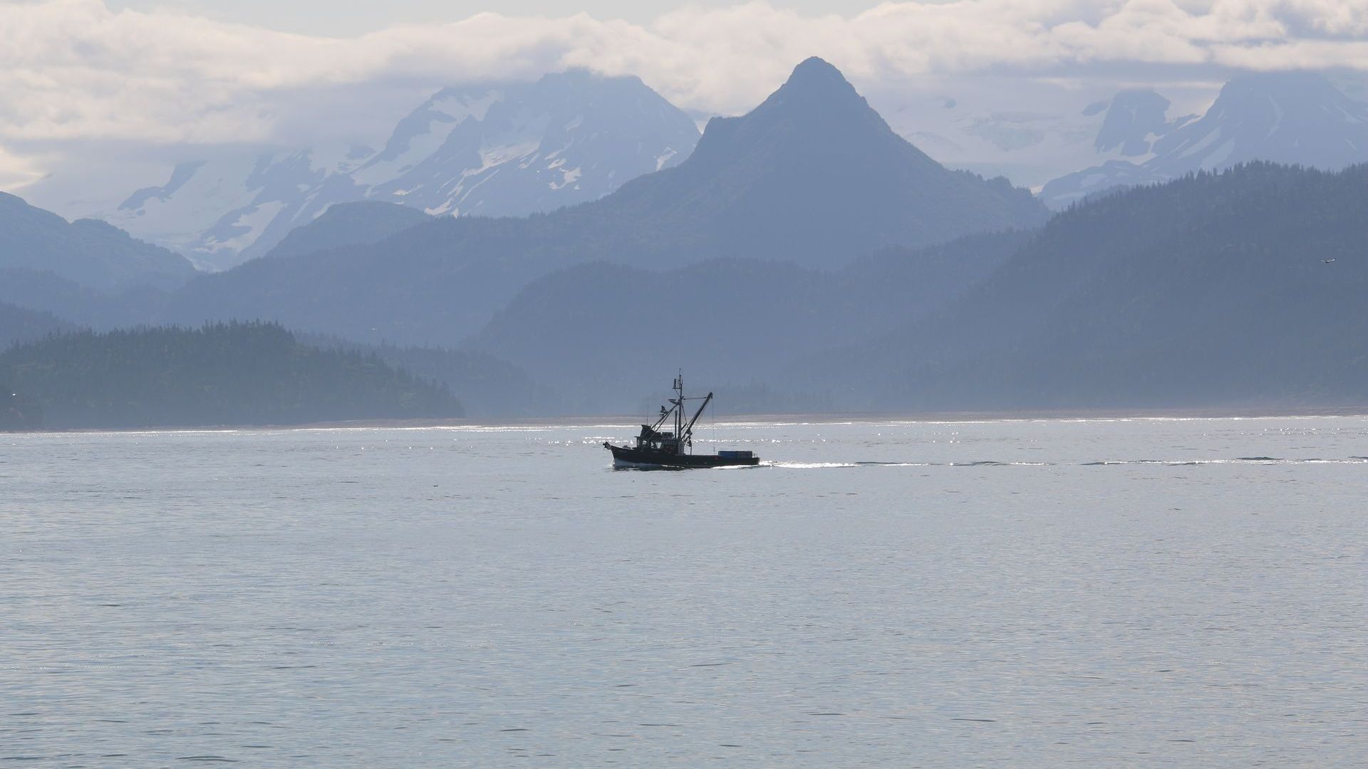 A boat is floating on top of a body of water with mountains in the background.