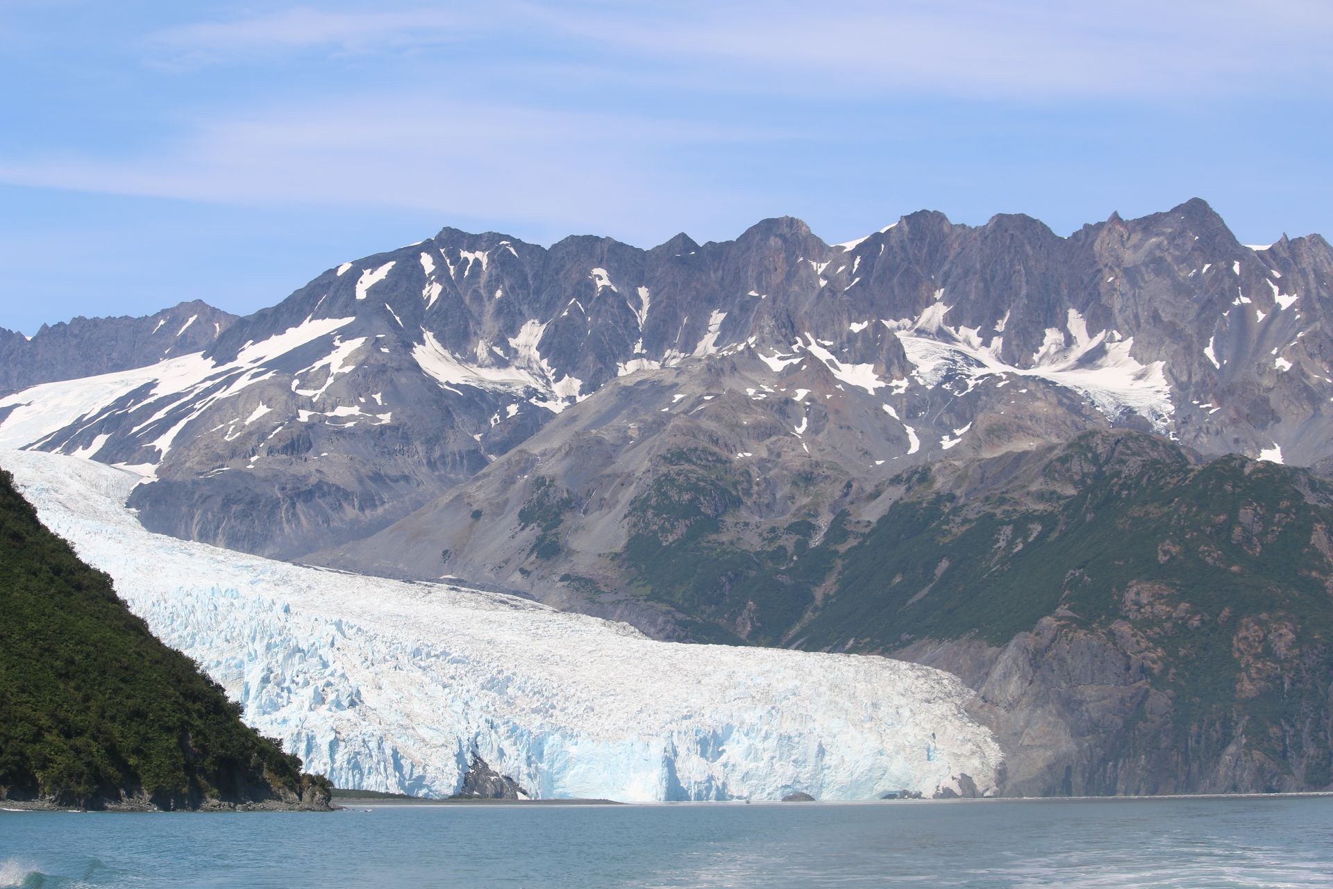 A glacier in the middle of a lake with mountains in the background
