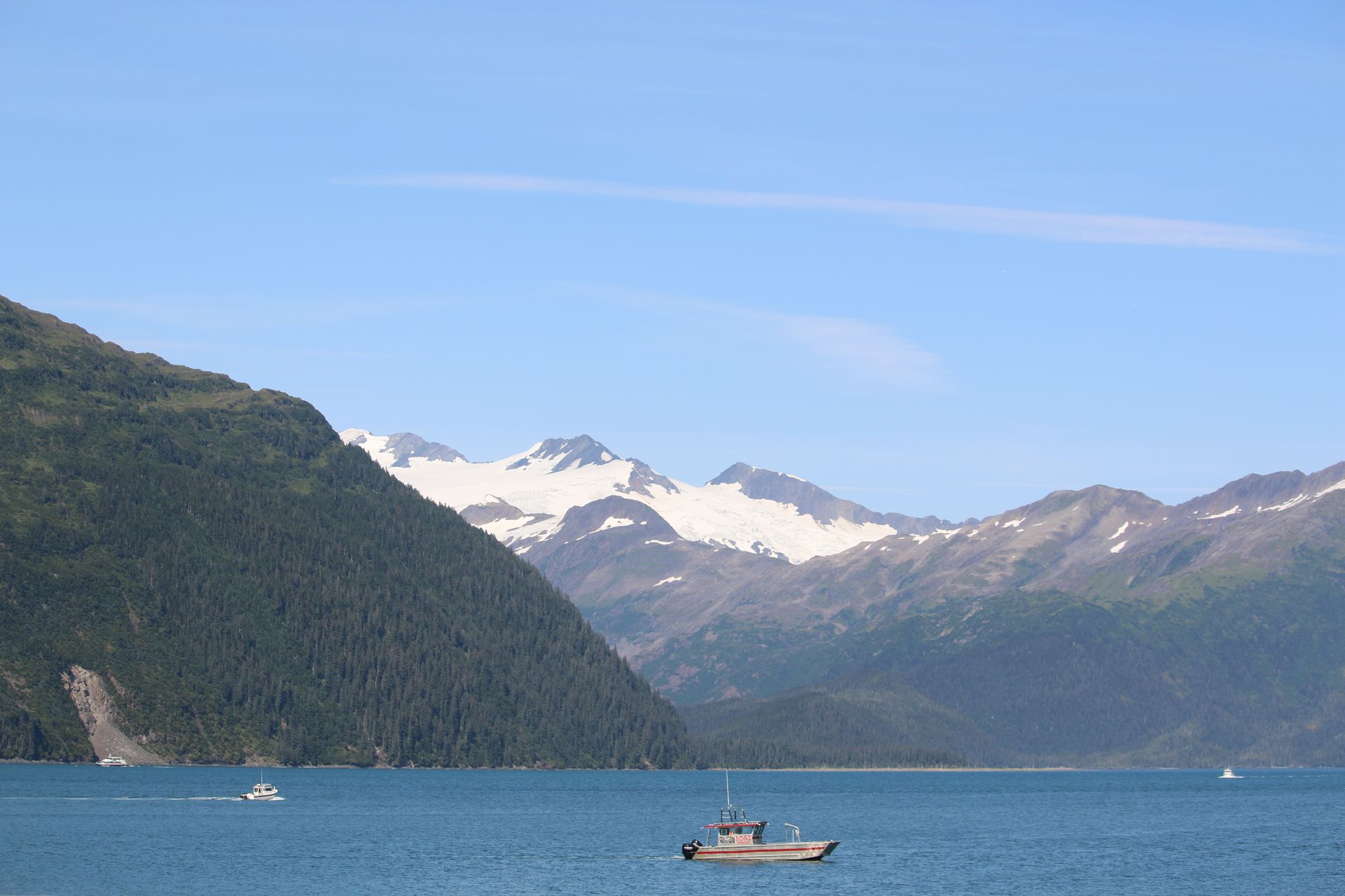 A boat is floating on a lake with mountains in the background.