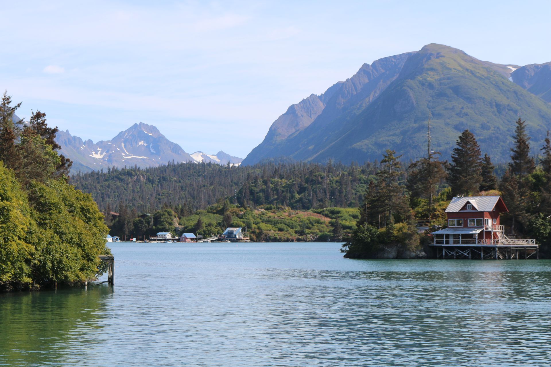 A house on a dock in the middle of a lake with mountains in the background