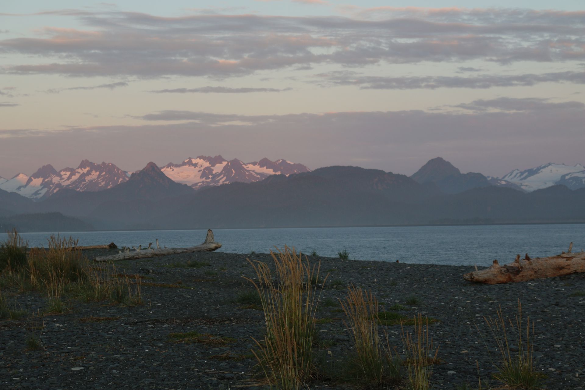 A boat is sitting on the shore of a lake with mountains in the background.