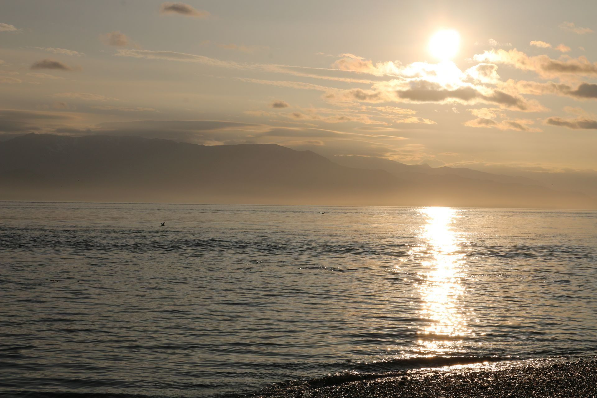 The sun is shining through the clouds over the ocean