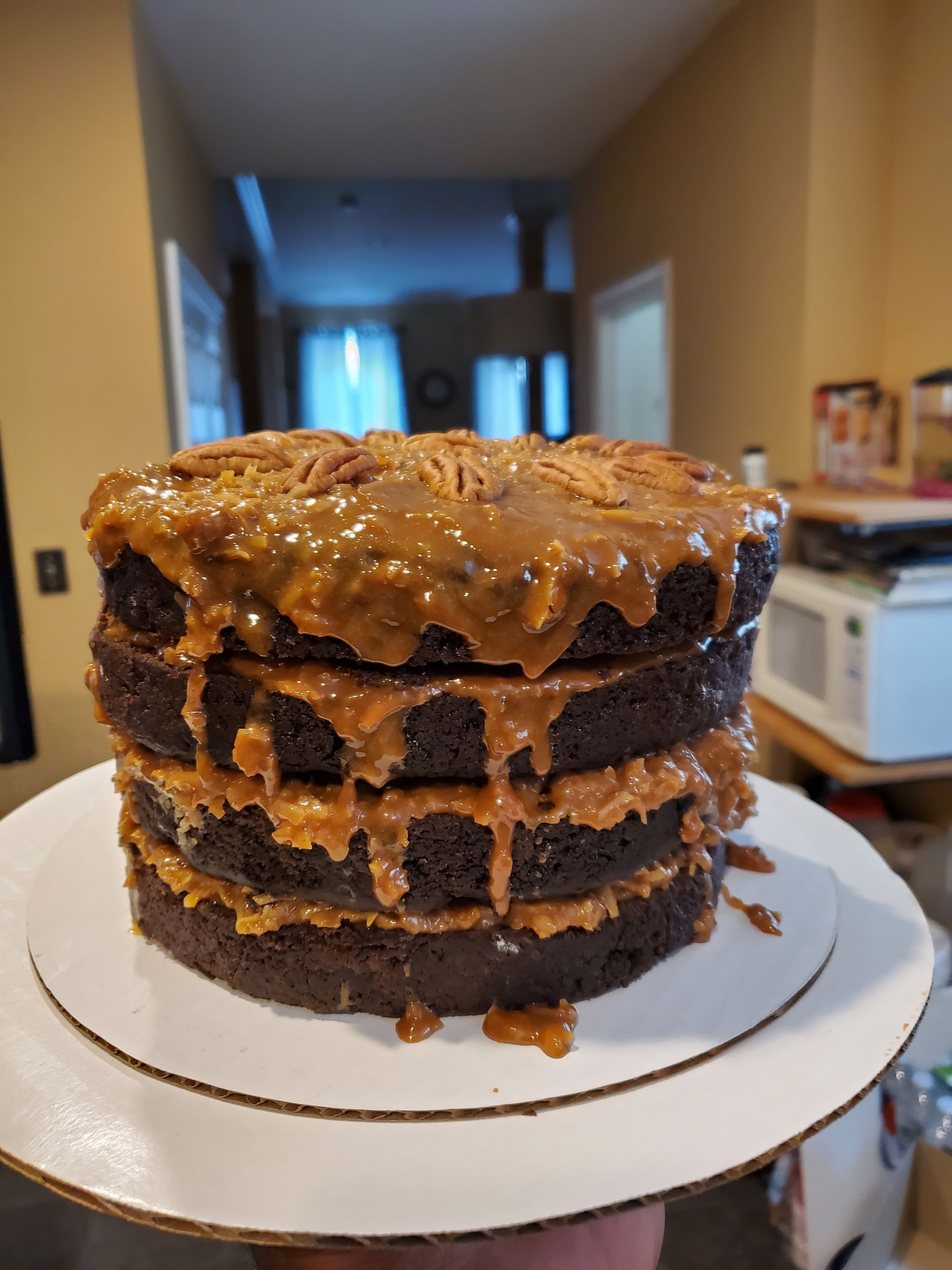 A person is holding a stack of chocolate cakes on a white plate.