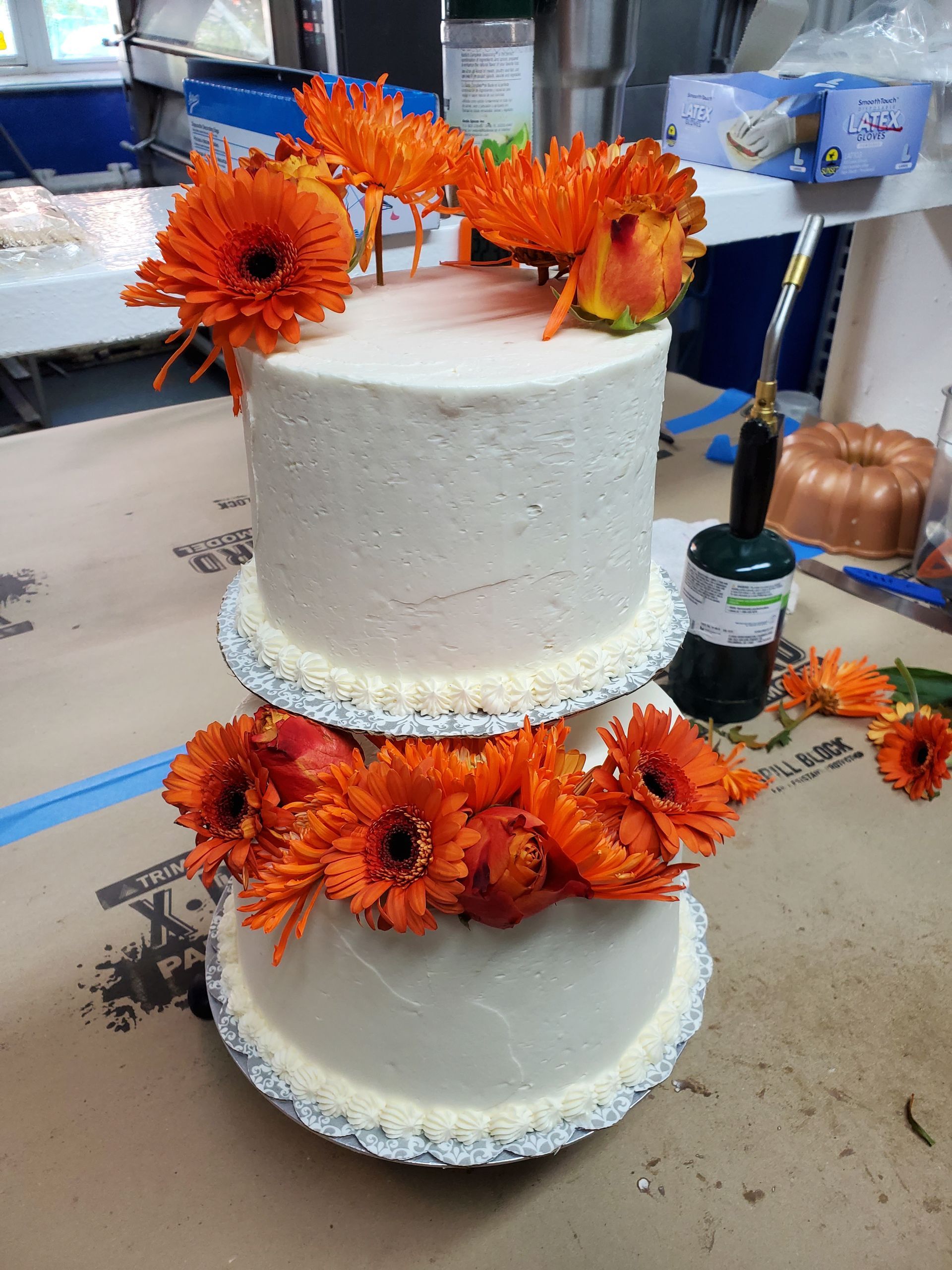A three tiered cake with orange flowers on top