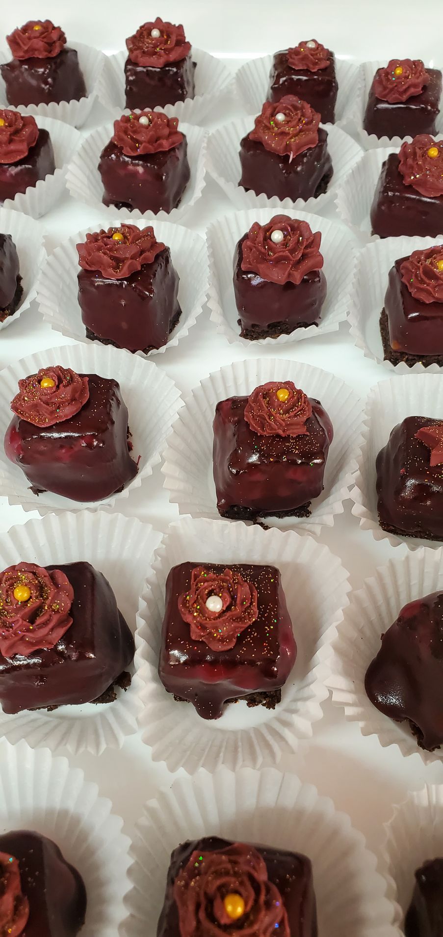 A tray of chocolate covered cupcakes with flowers on top.