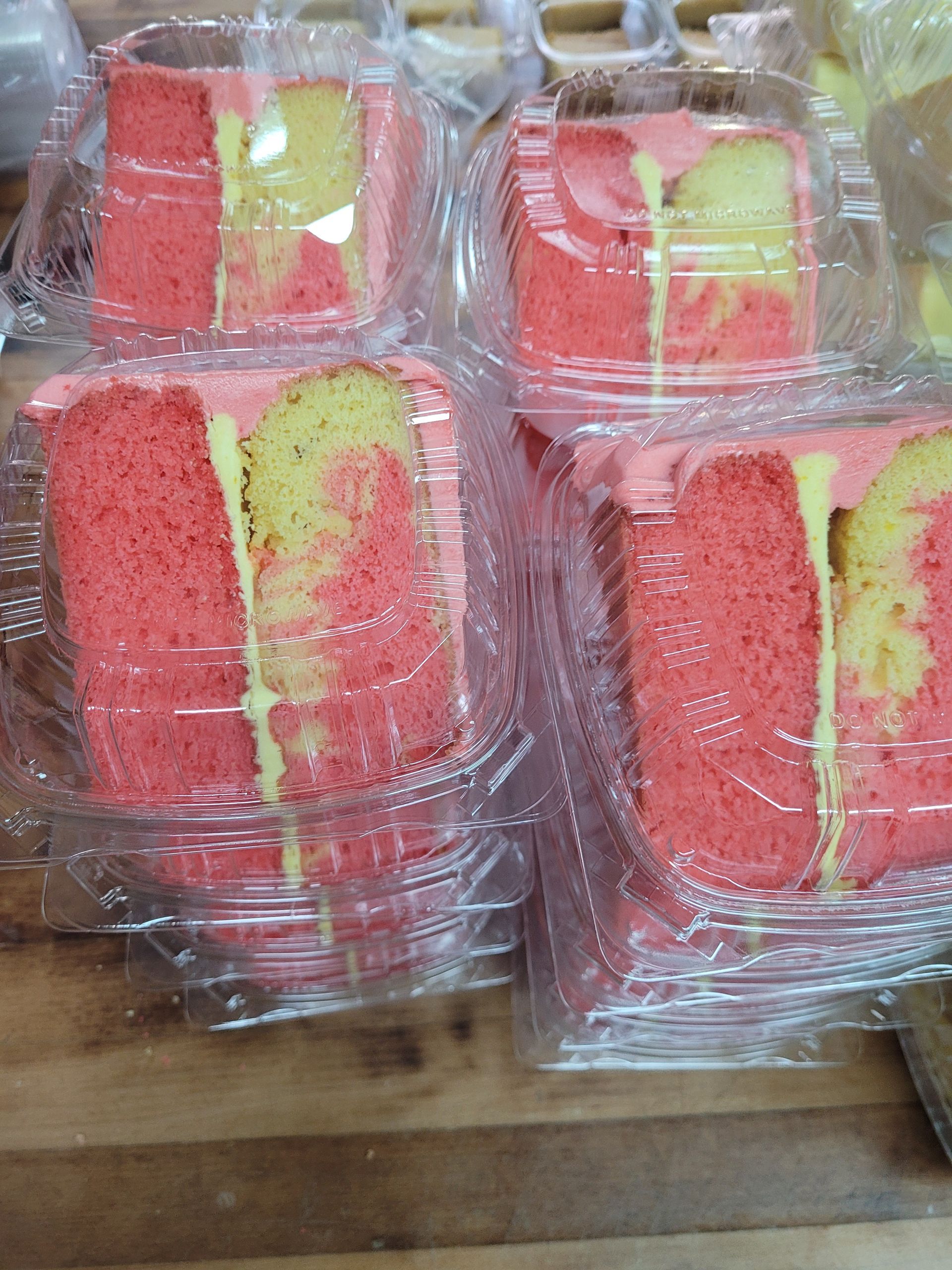 A bunch of slices of cake in plastic containers on a table.