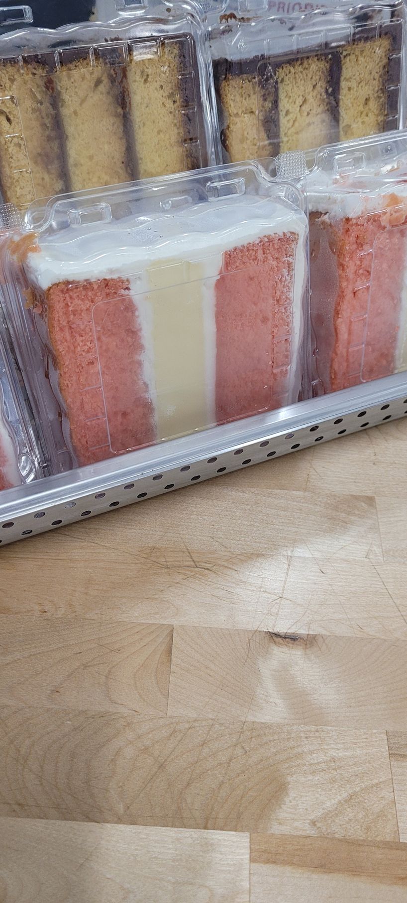 A tray of slices of cake on a wooden table.