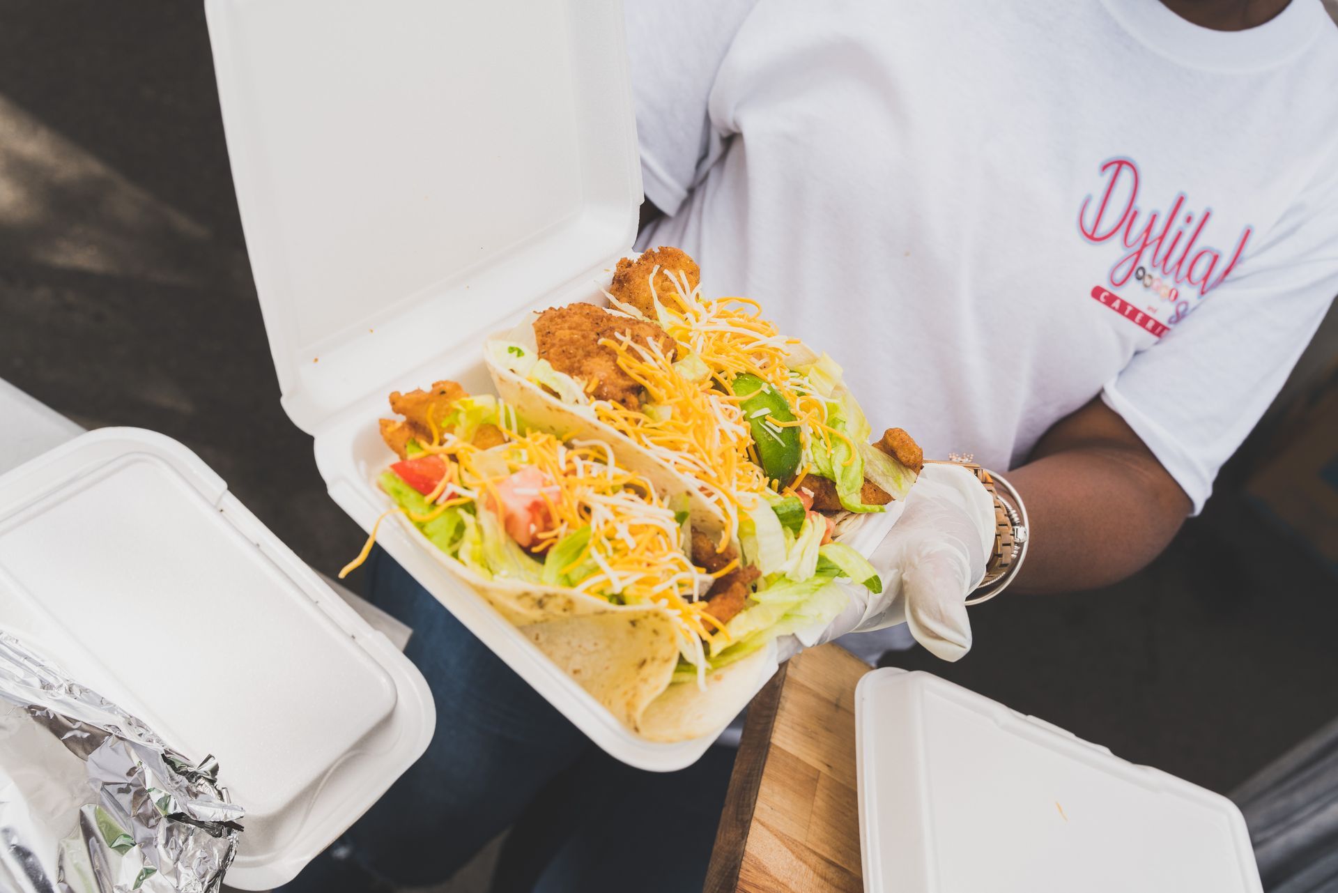 A person is holding a styrofoam container of tacos.