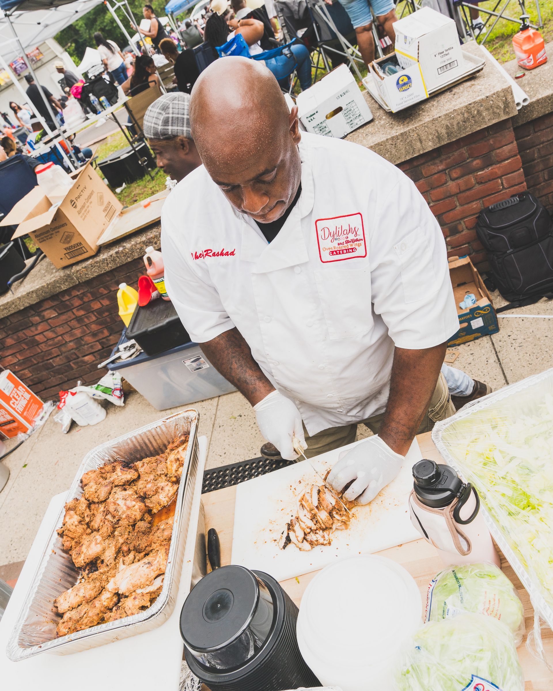 A man in a white shirt is cutting up food on a table.