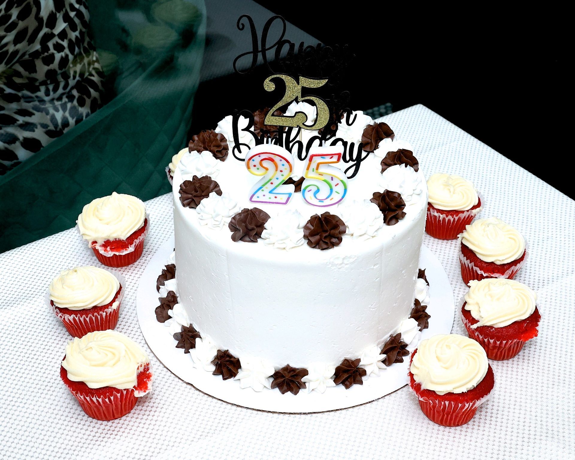 A birthday cake and cupcakes are on a table.