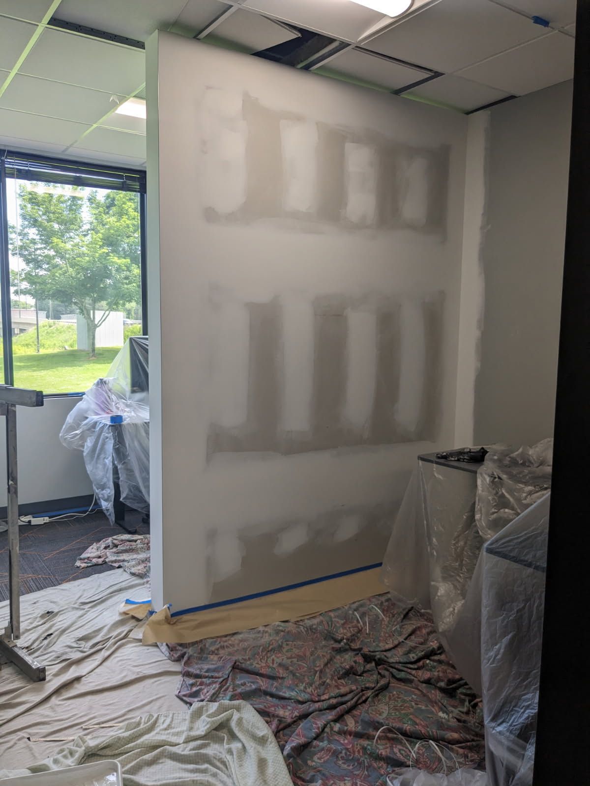 A room with a wall that is being painted.