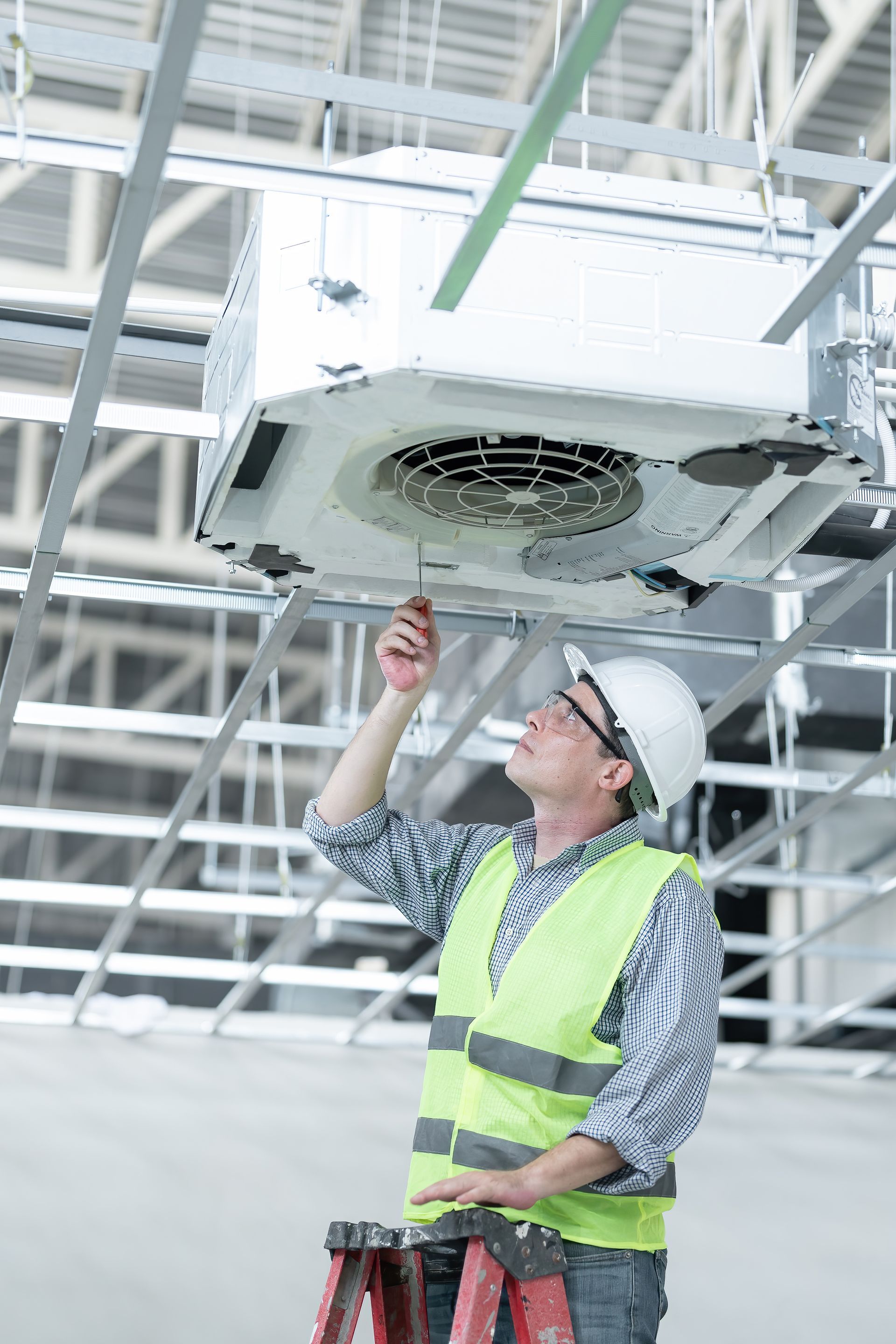 Un homme travaille sur un climatiseur dans un immeuble.