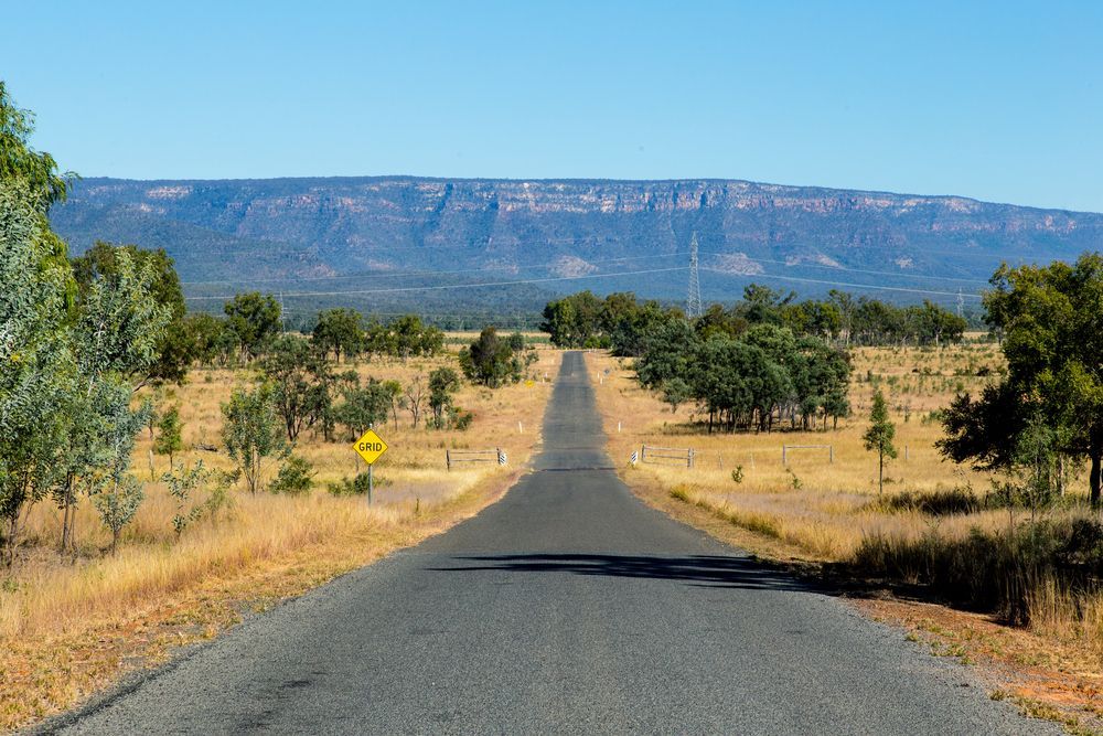 A Road Going Through a Desert With a Mountain in the Background — Davidson's Electrical In Central Highlands, QLD
