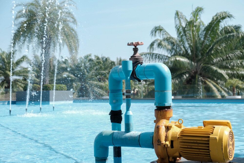 A Yellow Pump is Sitting Next to a Swimming Pool — Davidson's Electrical In Central Highlands, QLD