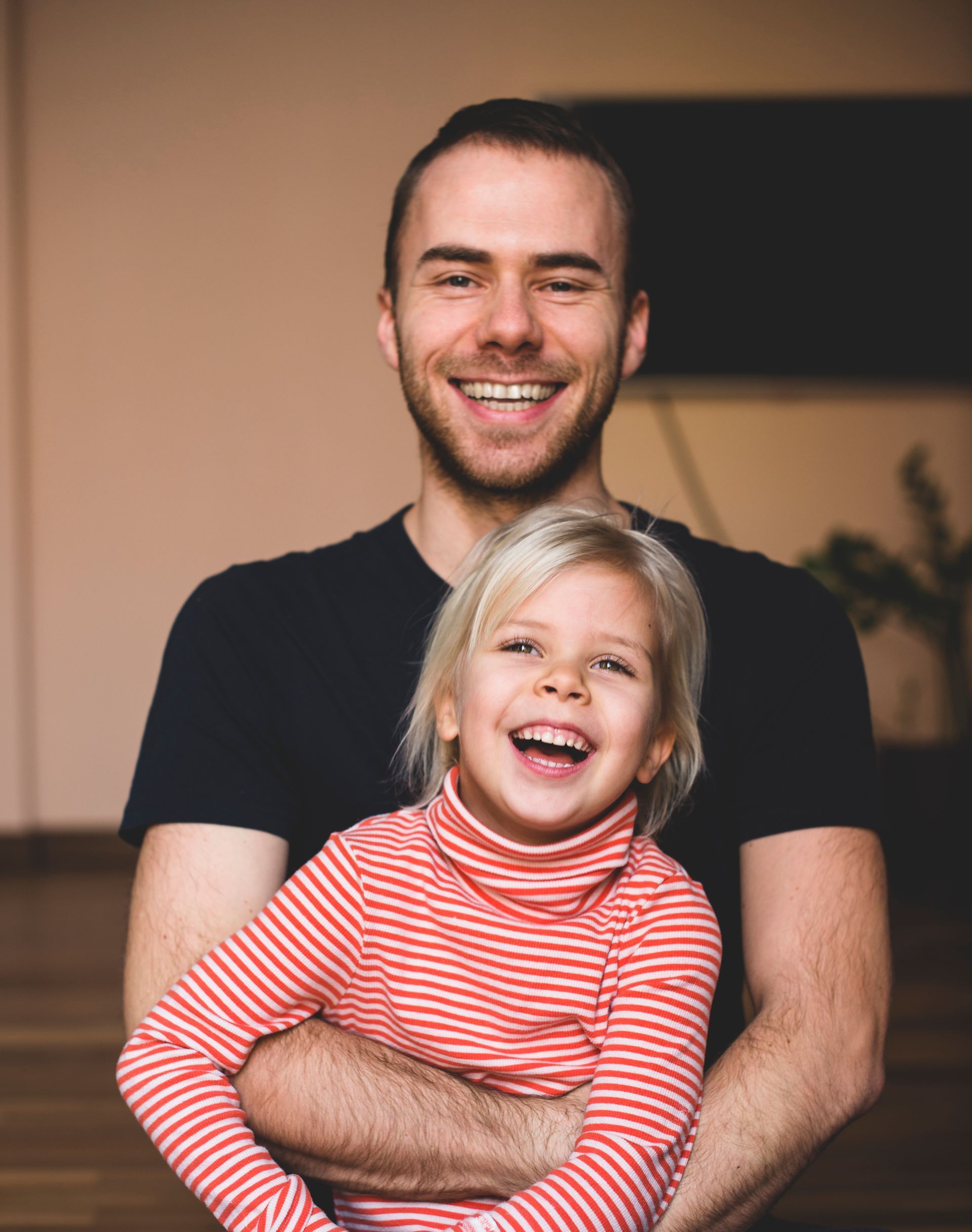 A woman in a yellow shirt is smelling a sunflower in a field.