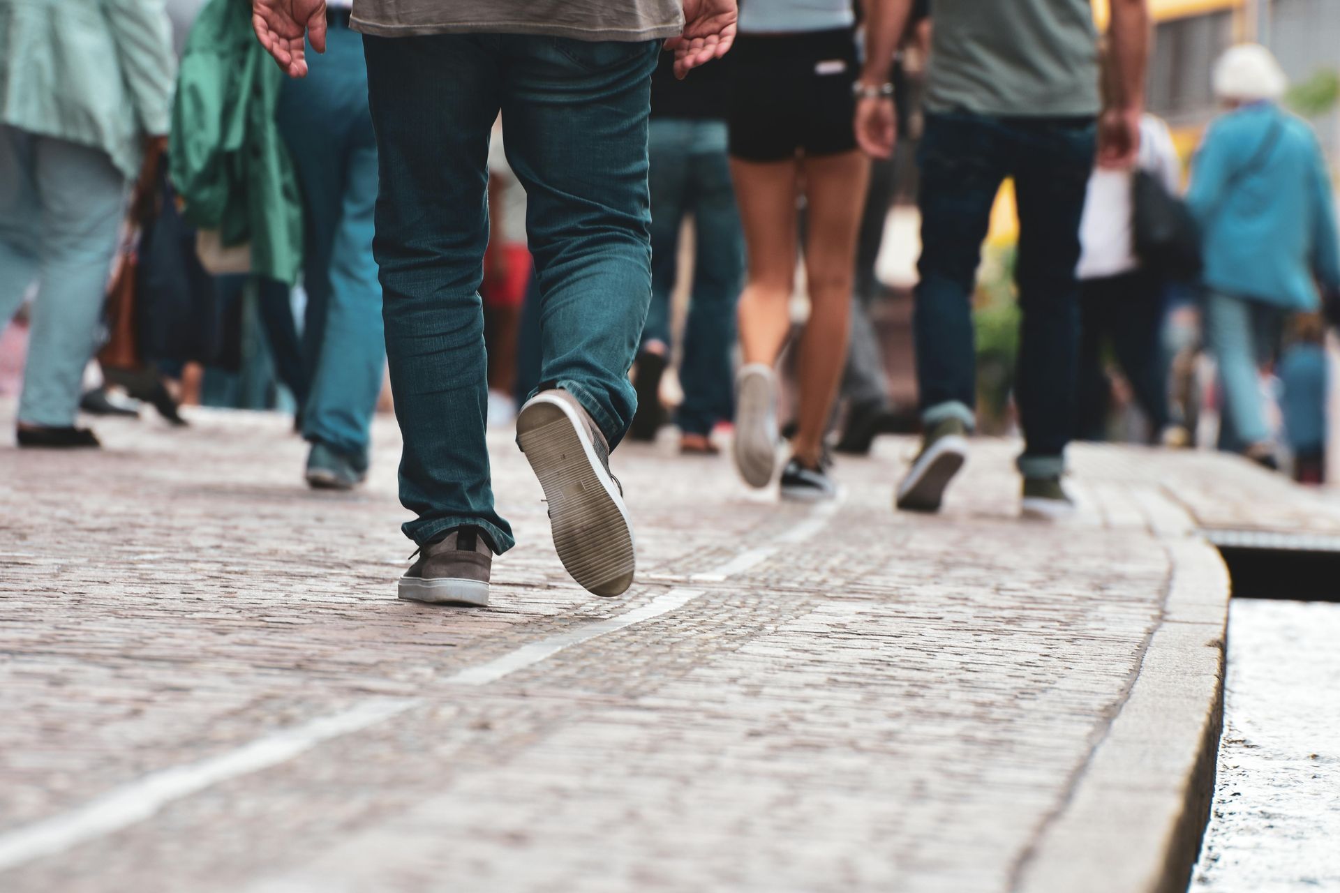 People walking on a cobblestone street in a busy city scene