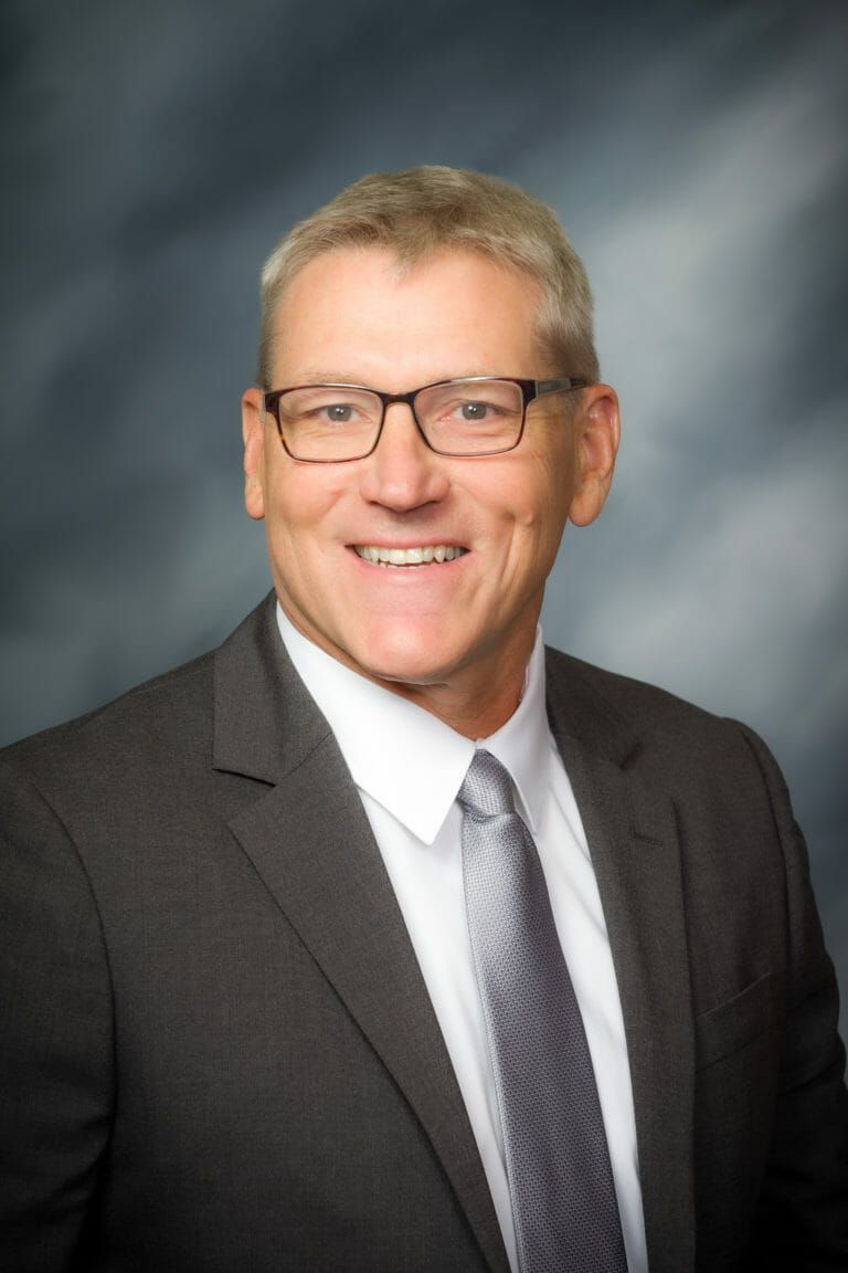 A man in a suit and tie is smiling for the camera.