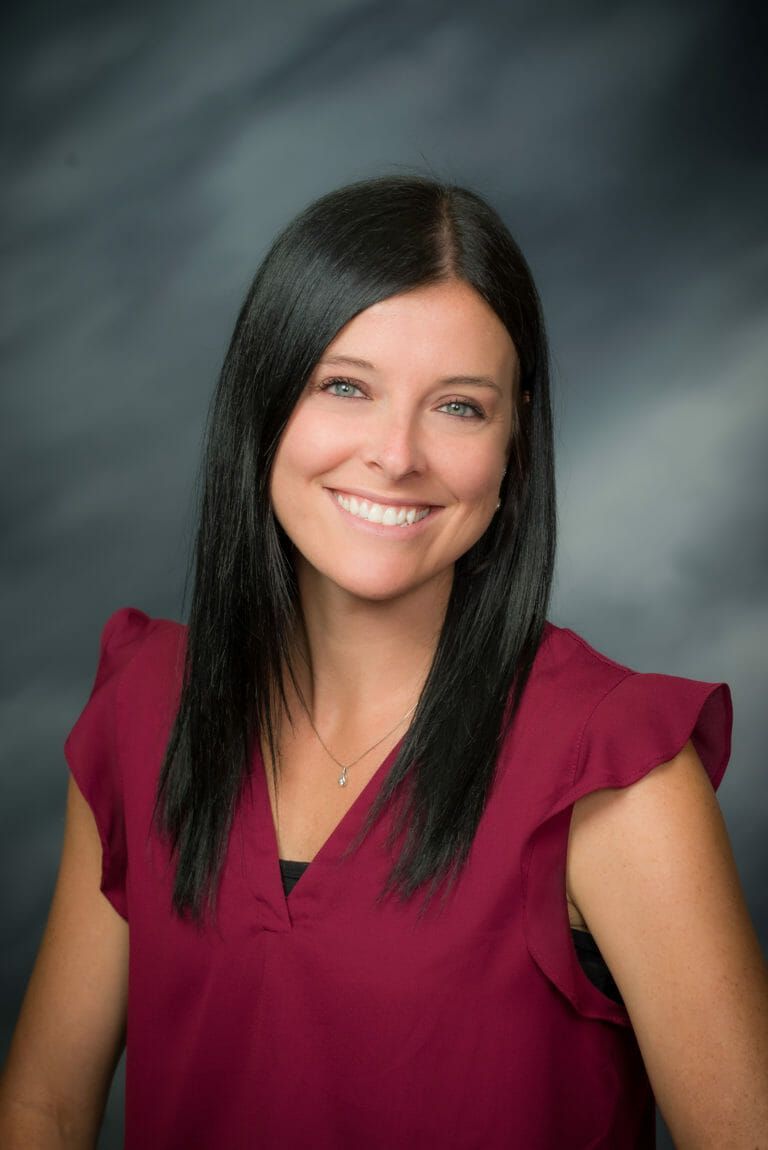 A woman in a red shirt is smiling for the camera.