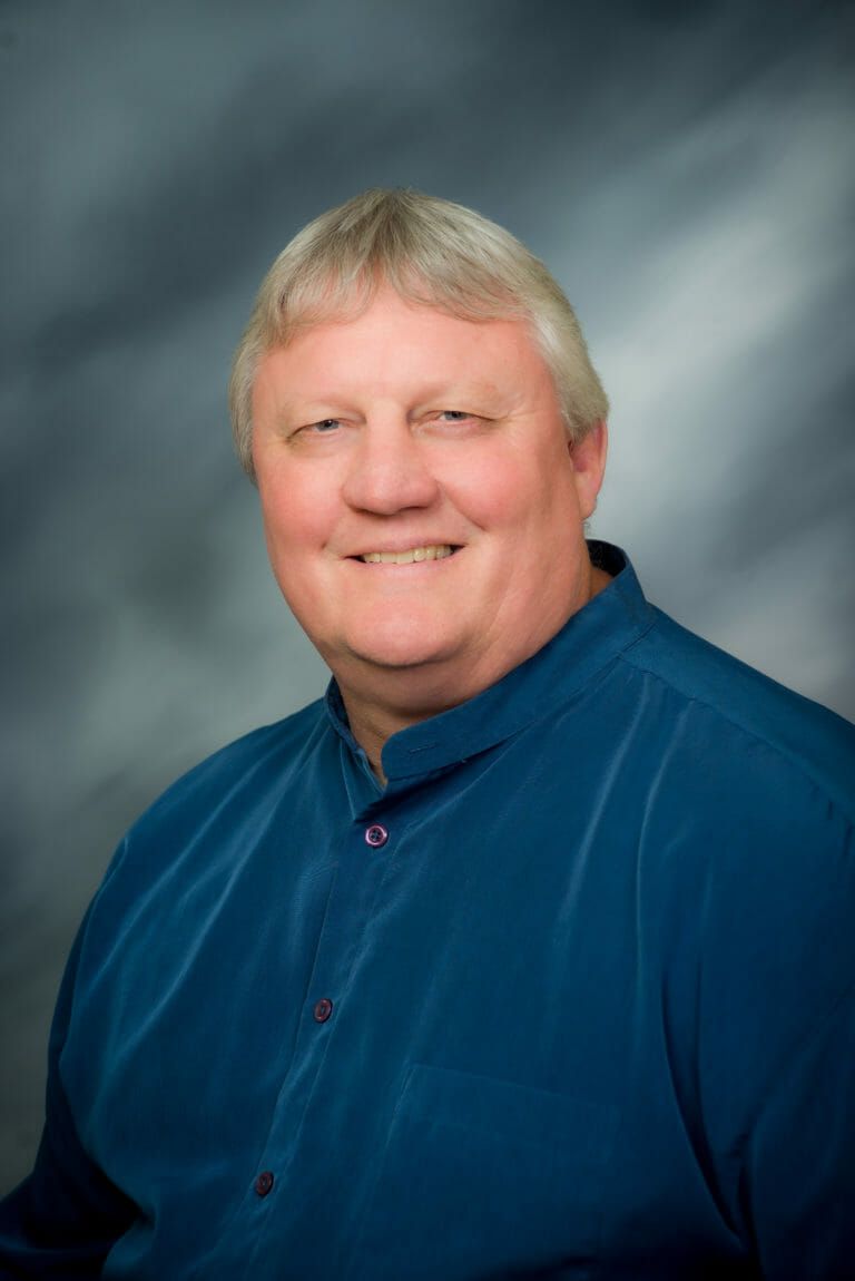 A man in a blue shirt is smiling for the camera