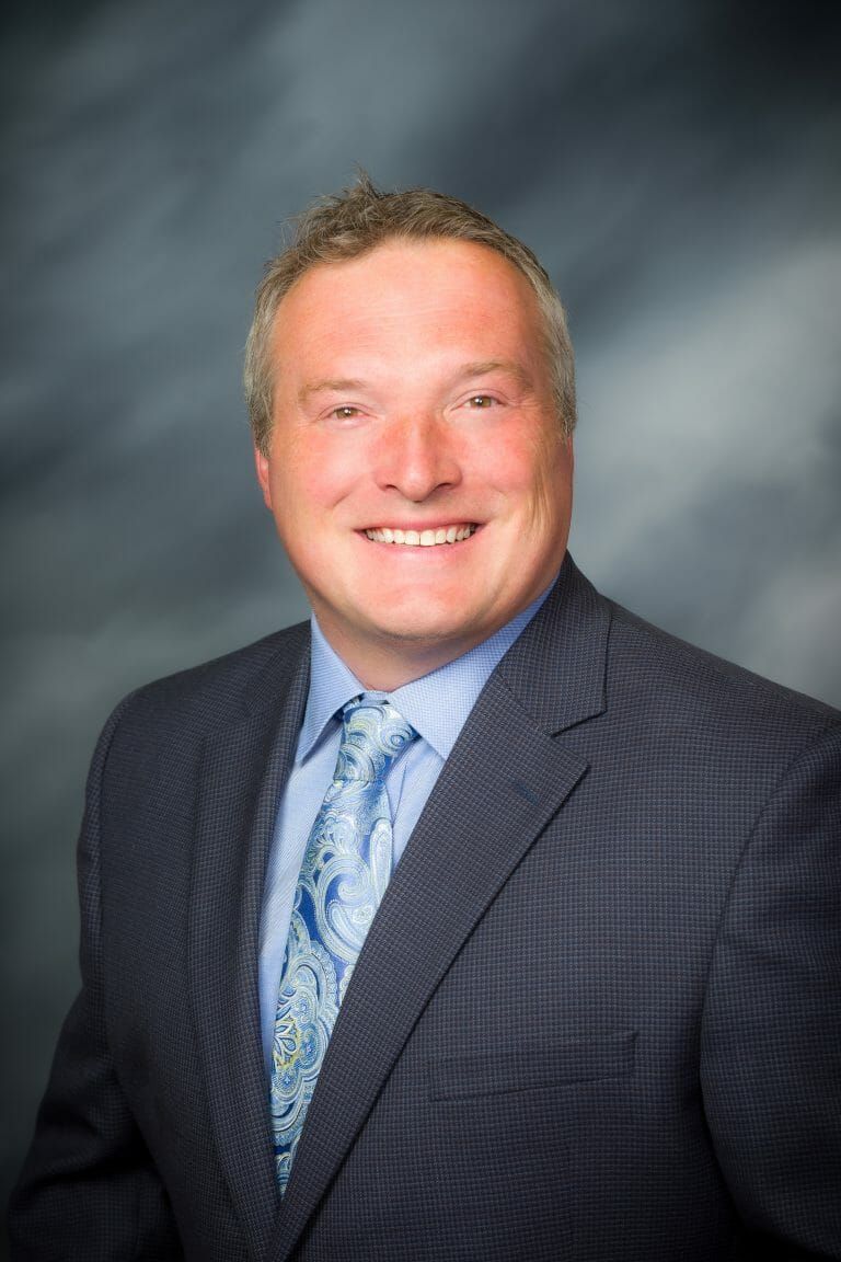 A man in a suit and tie is smiling for the camera.