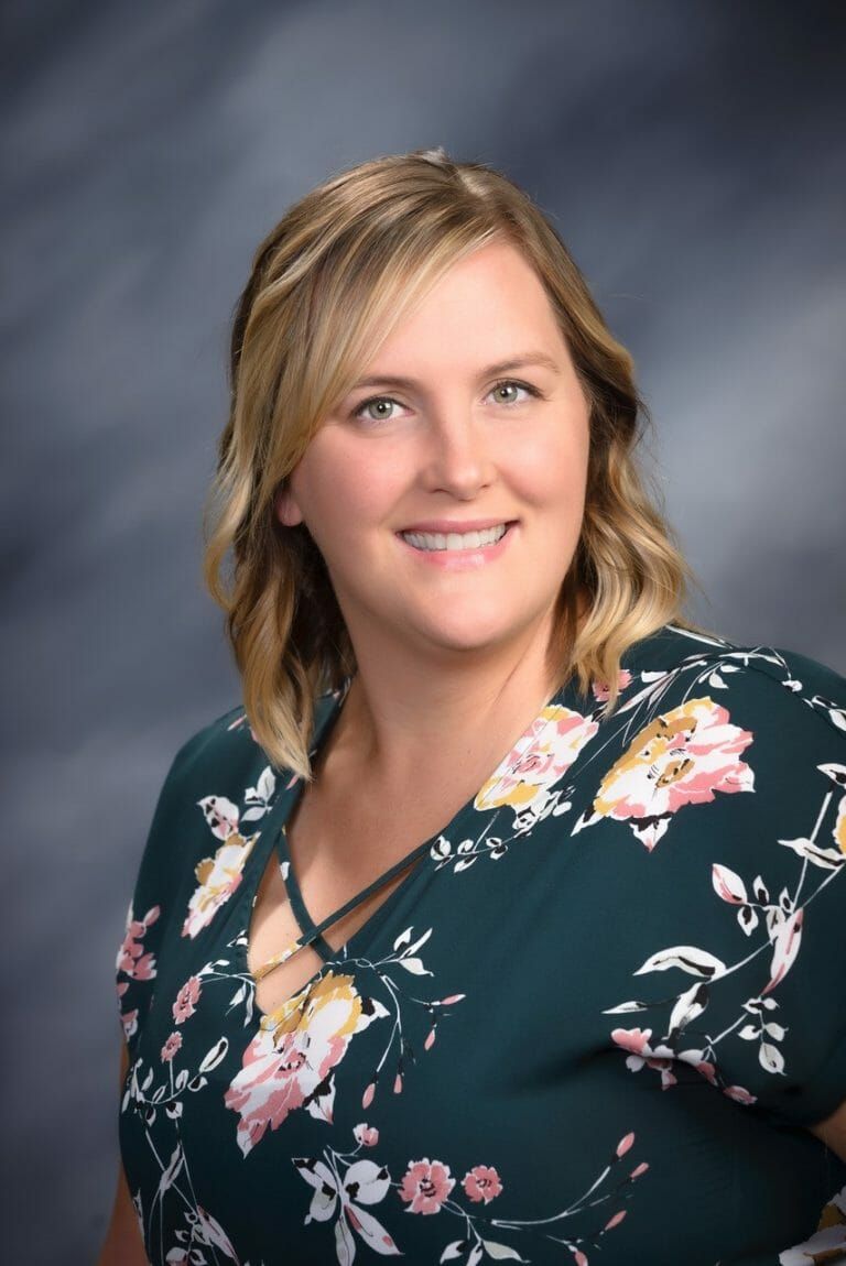 A woman in a floral shirt is smiling for the camera.