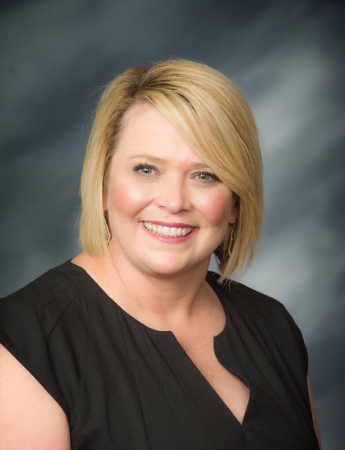 A woman in a black dress is smiling for the camera.