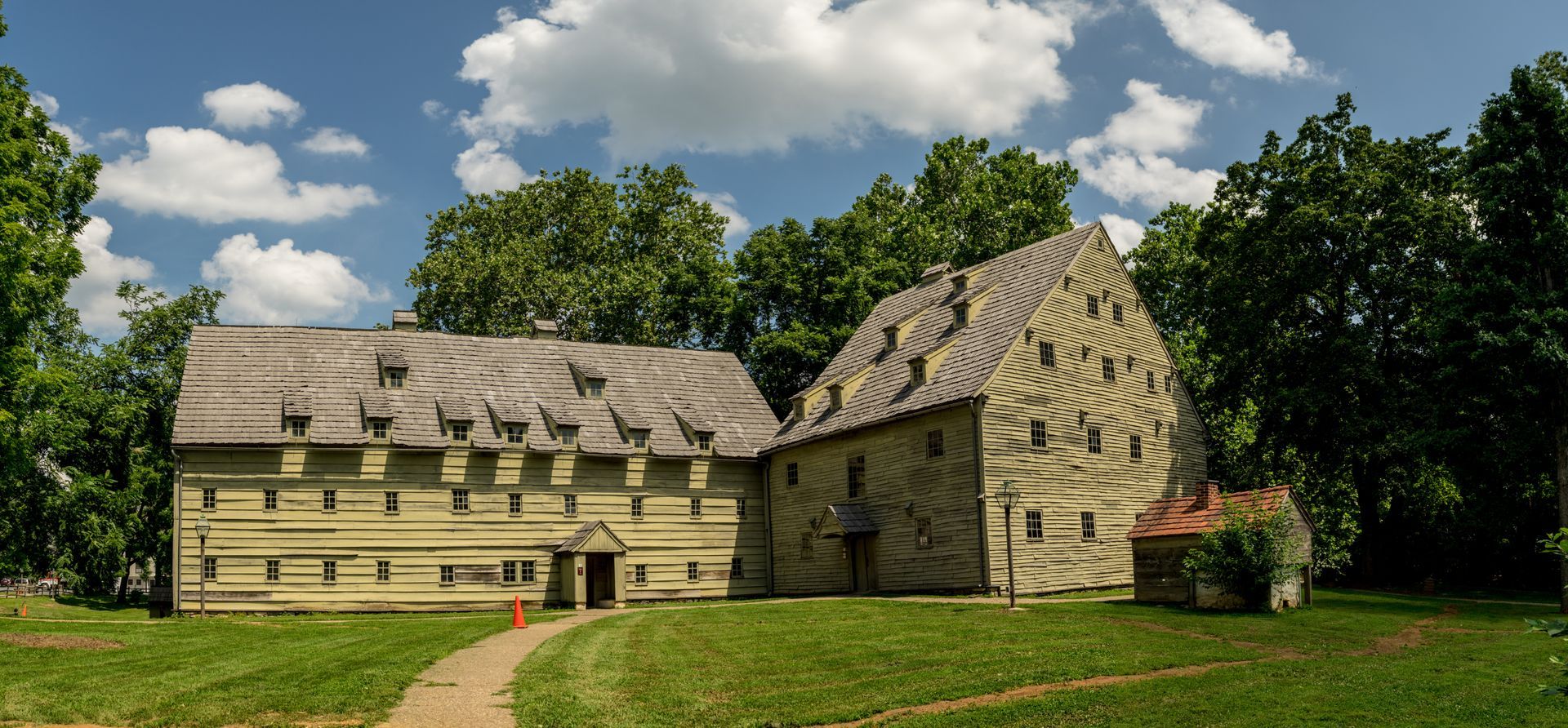 A large building with a wooden roof is surrounded by trees and grass.
