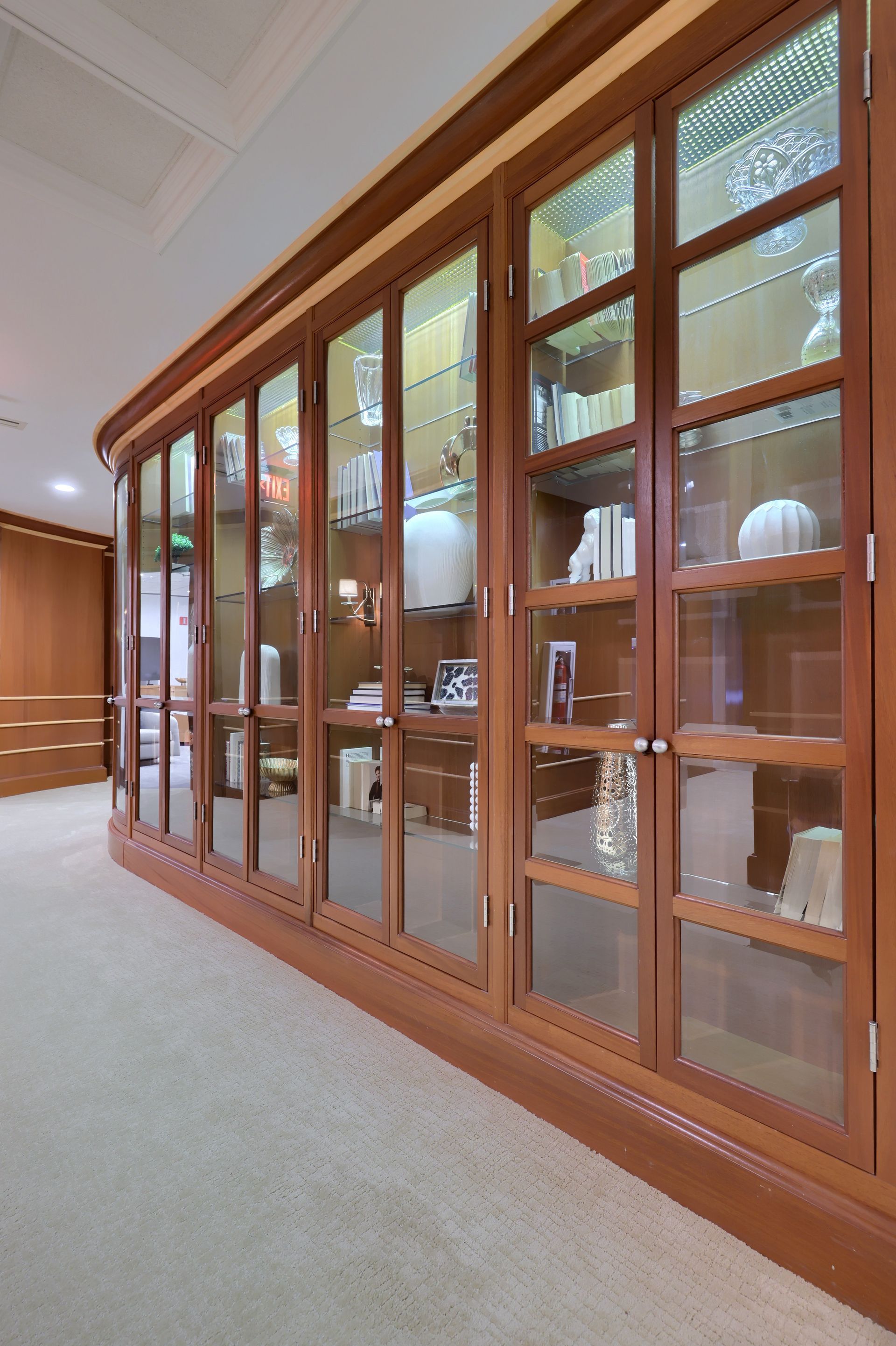 A hallway with a glass cabinet filled with vases and books