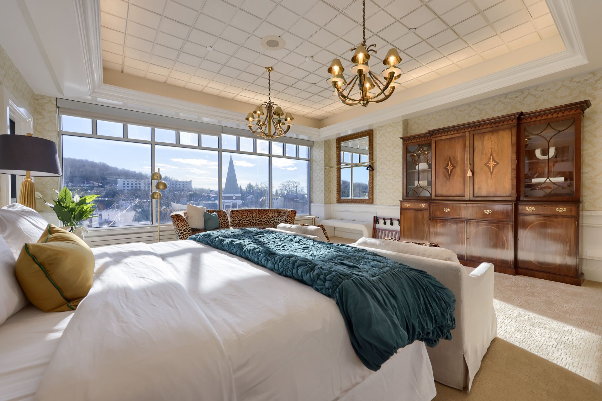 A bedroom with a king size bed , a couch , and a chandelier.