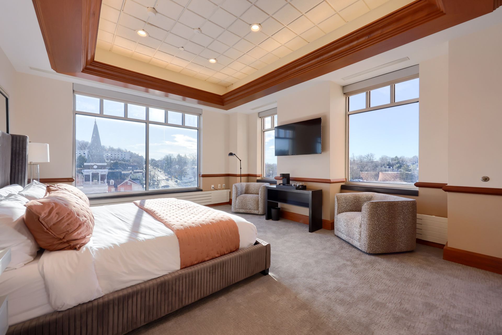 A hotel room with a large bed , chairs , desk and television.