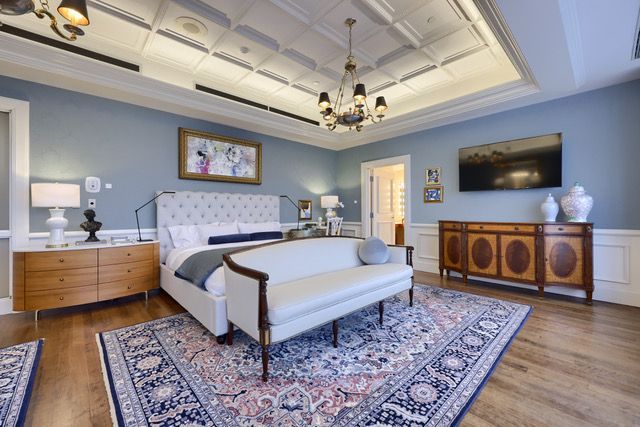 A bedroom with a large bed , couch , rug and television.