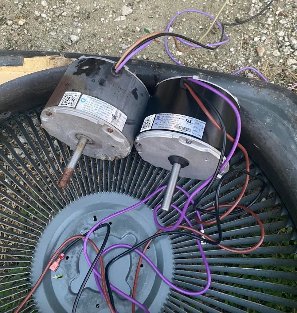 Two black electric motors with wires atop a fan blade.