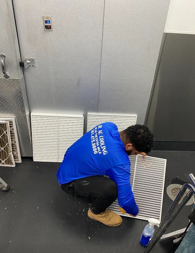 Man in blue shirt replacing air filters indoors.