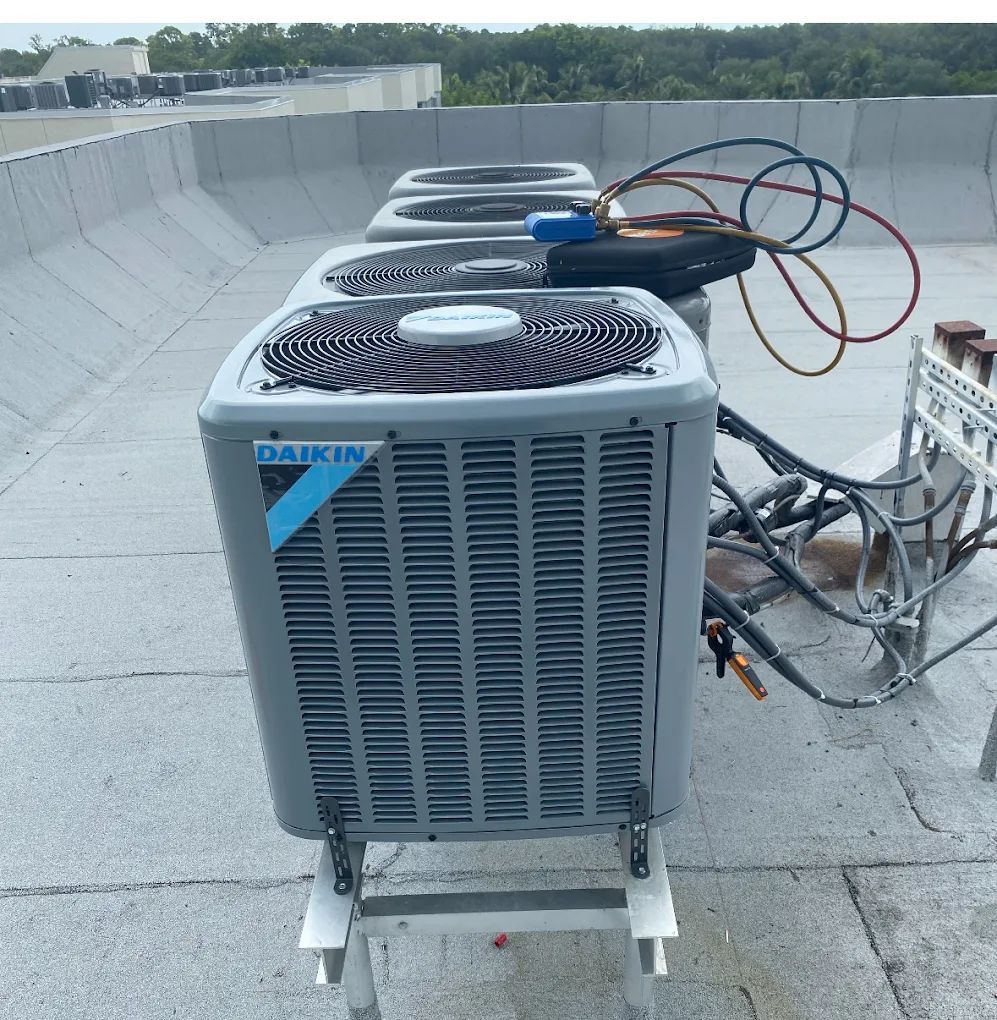 Daikin AC units on a flat roof, with gauges and hoses connected for maintenance.