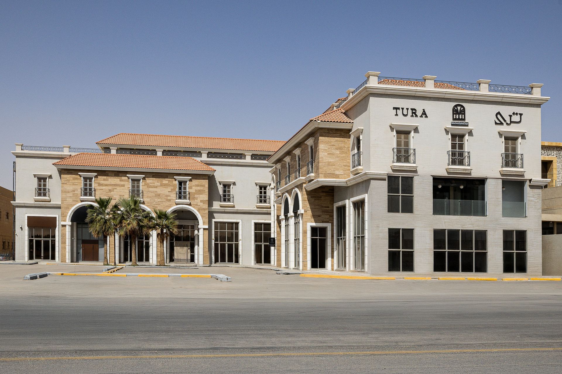 A multi-story building with tan stone and grey sections, featuring arched entrances and a 