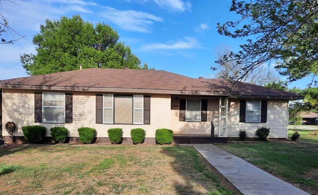 A white house with a brown roof and black shutters