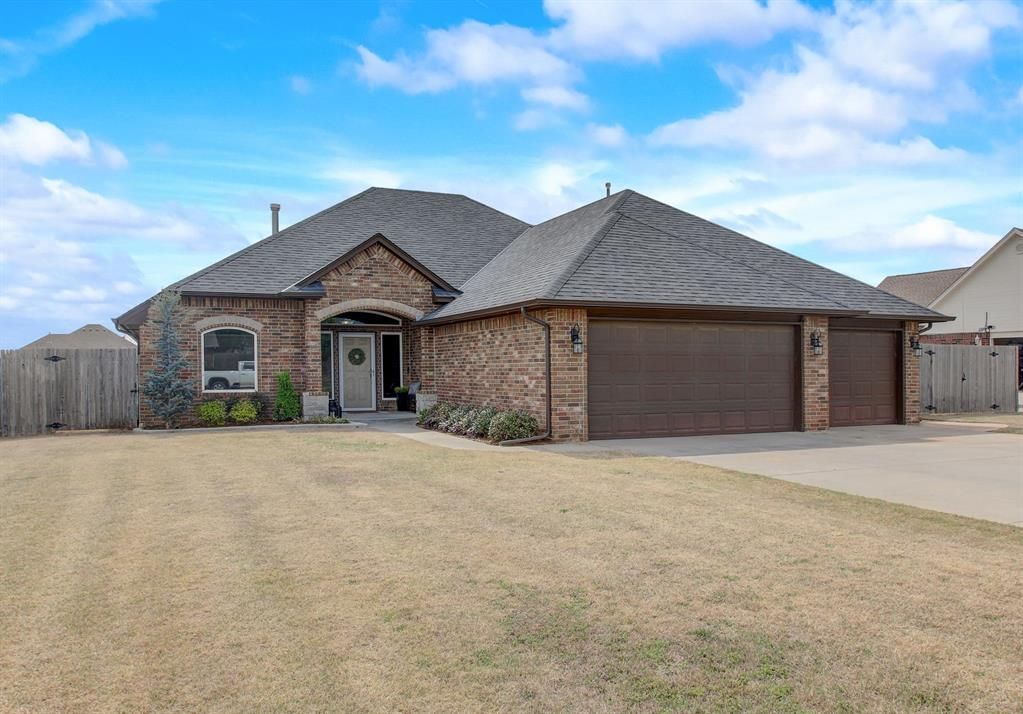 A large brick house with a large garage and a fence in front of it.