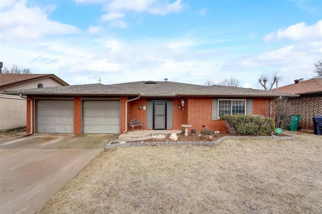 A red brick house with two garages and a gravel driveway.