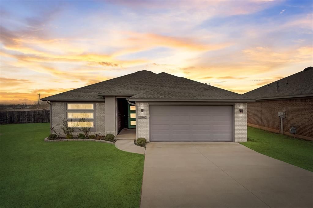 A house with a gray garage door and a sunset in the background.