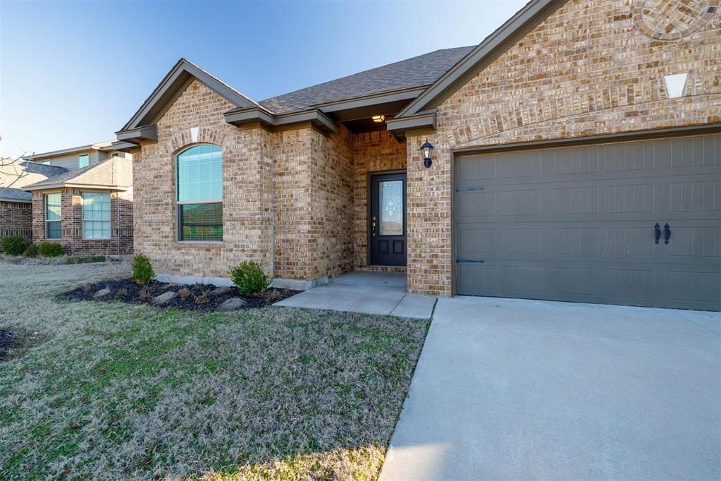 A brick house with a garage and a driveway in front of it.