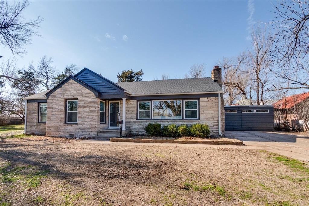 A brick house with a gray roof is sitting on top of a dirt field.