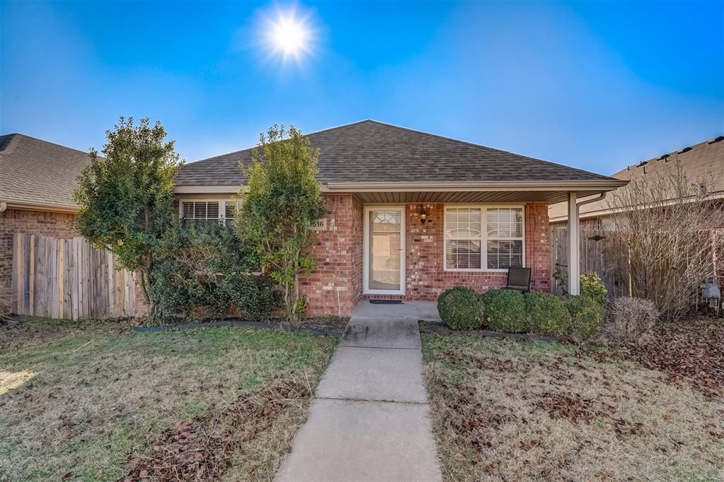 A brick house with a concrete walkway leading to it.