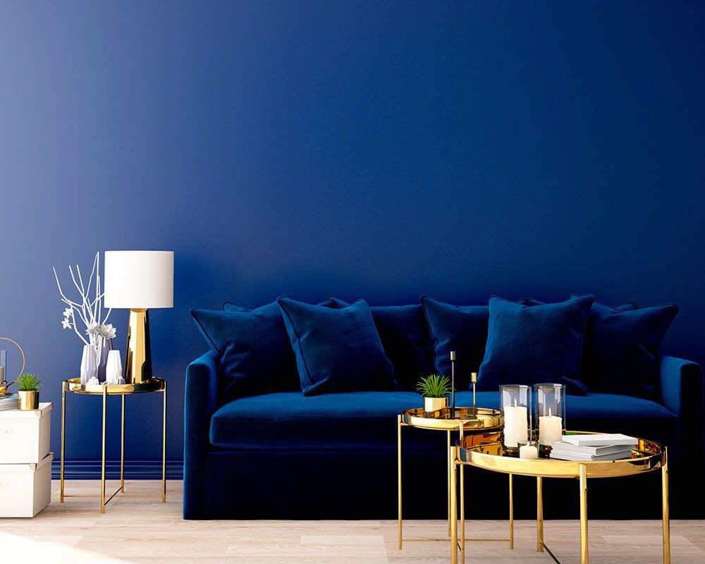 Una sala de estar con un sofá azul y dos mesas doradas.