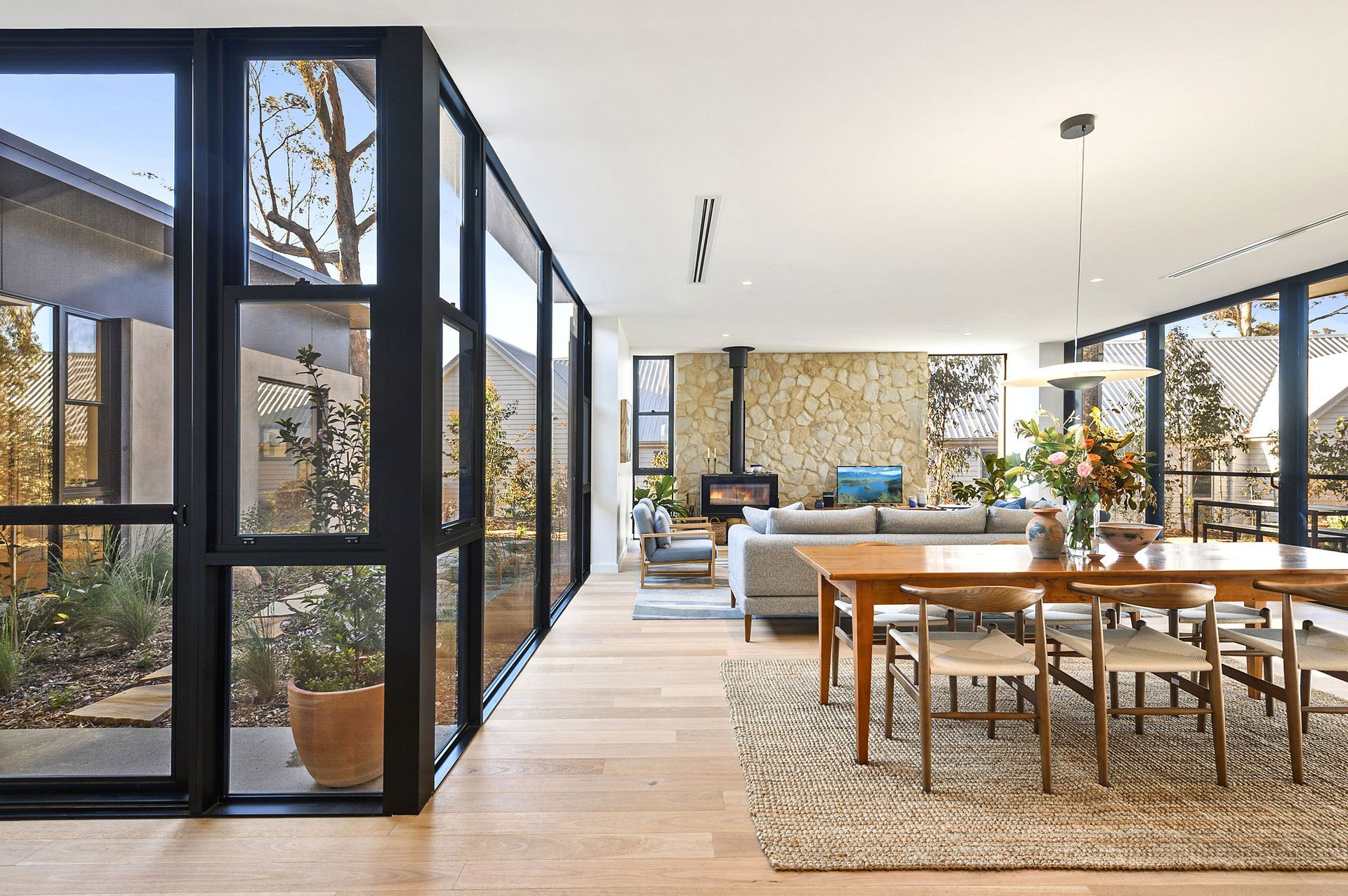 A living room and dining room in a house with lots of windows.
